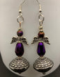 A pair of purple earrings featuring metal angel wings and a metal pedestal, designed for love and positivity.